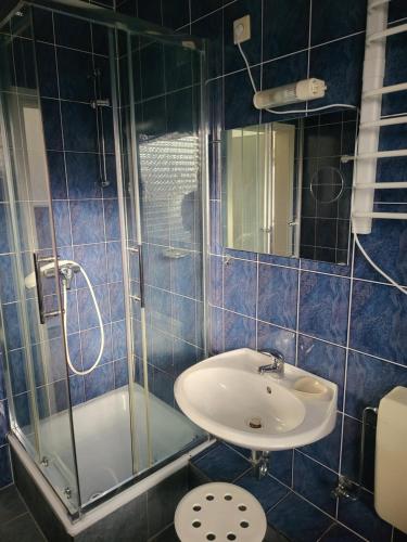 a blue tiled bathroom with a sink and a shower at Hotel Schlaun in Nordkirchen