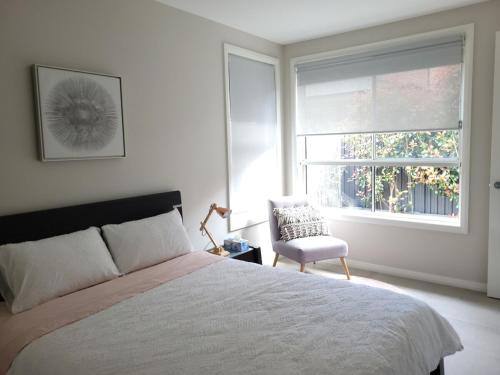 a bedroom with a bed and a chair and a window at Cosy Private Modern Flat in Epping