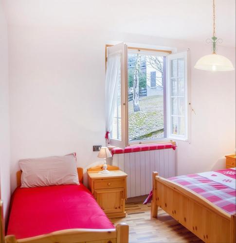 a bedroom with two beds and a window at Ca' Maria - Casa in Scalve in Schilpario
