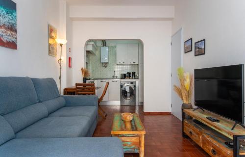 a living room with a blue couch and a tv at Casa da Flor in Lagos in Lagos