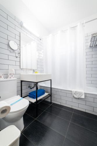 a white bathroom with a sink and a toilet at Kefalos Beach Tourist Village in Paphos