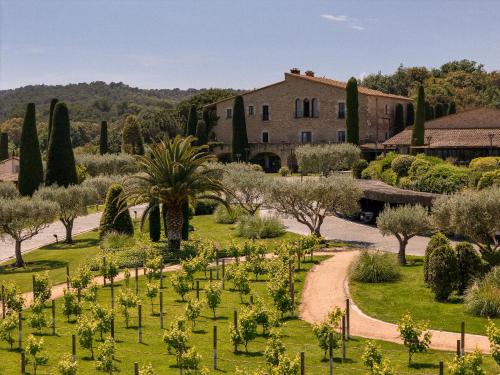 a garden with trees and a building in the background at Mas de Torrent Hotel & Spa, Relais & Châteaux in Torrent