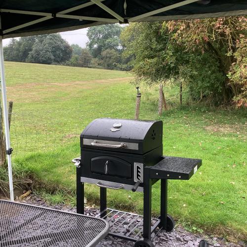 a grill sitting under a tent in a field at Wooded Bubble in Kent