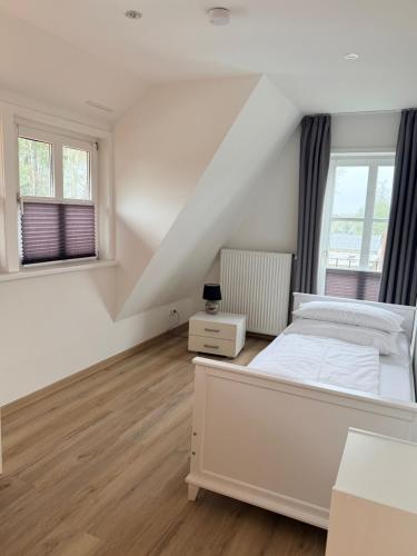 a white bedroom with a bed and two windows at Ferienwohnung Brigitta in Hambühren