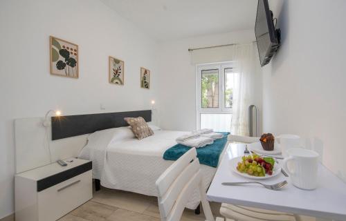 a white bedroom with a bed and a table with a bowl of fruit at The Chairs Place GuestHouse in Lagos