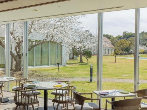 a restaurant with tables and chairs and a large window at Mercure Fukuoka Munakata Resort & Spa in Munakata