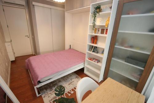 a small bedroom with a pink bed and shelves at Foz Palace - Praia da Rocha in Portimão