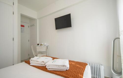a white room with a bed with towels on it at The Chairs Place GuestHouse in Lagos