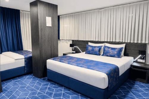 a hotel room with a large bed with blue sheets at Hotel Biga in Zavidovići