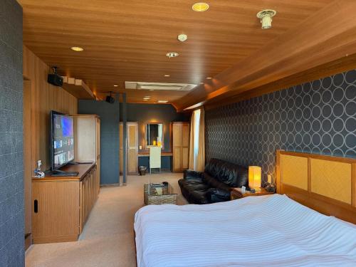 a bedroom with a bed and a couch and a television at HOTEL AMARIS & HIP (Adult Only) in Kanazawa