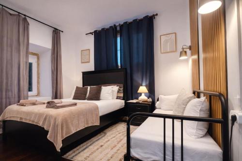 two beds in a room with blue curtains at Happy Holiday Sintra Guesthouse & Breakfast in Sintra