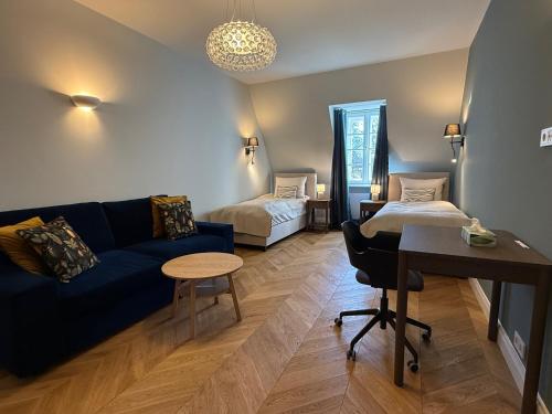 a living room with a blue couch and a bed at Apartament Kirkor przy Dworku Bielin in Bielin