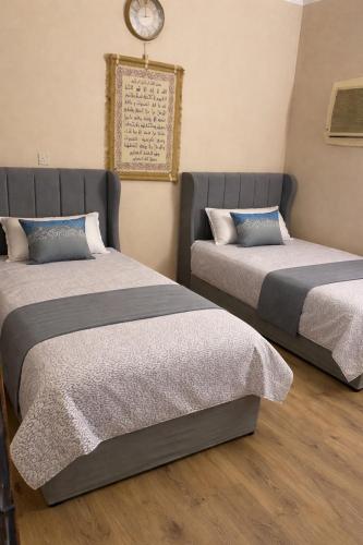 two beds in a room with a clock on the wall at RUBA apartment in Dammam