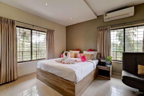 a bedroom with a bed and a couch and windows at Kohinoor Exotica in Lonavala