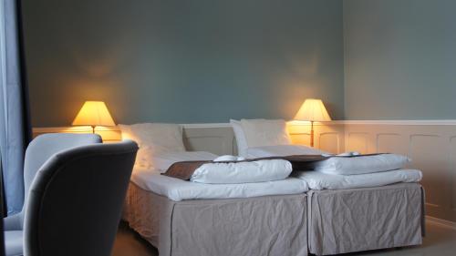 a bed with four pillows on it with two lamps at Marina Hotel Sortland in Sortland