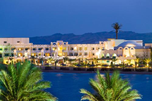 a view of a resort at night with palm trees at Coral Sun Beach in Safaga 