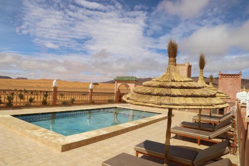 a swimming pool with two lounge chairs and an umbrella at Ouzina Desert Camp in Ouzina