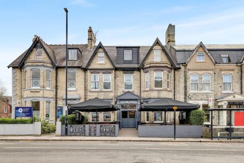 a large brick building with umbrellas in front of it at The Jam Jar, Newcastle, Jesmond in Jesmond
