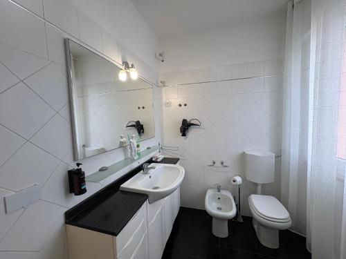 a white bathroom with a sink and a toilet at The Desdemona in Pordenone