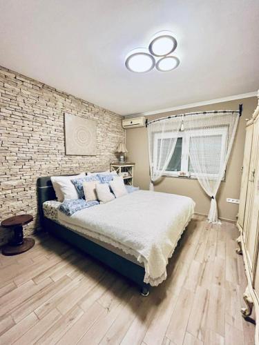 a bedroom with a bed and a brick wall at Nirvana Apartman in Balatonberény