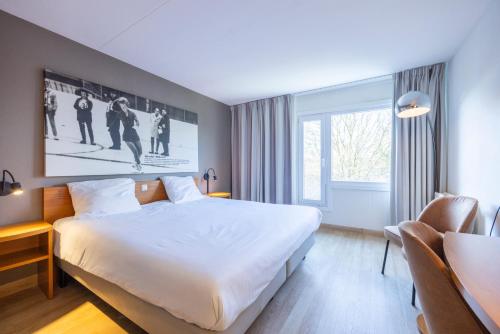 a hotel room with a large bed and a window at Fletcher Resort-Hotel Zutphen in Zutphen
