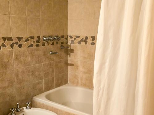 a bathroom with a tub and a toilet and a shower curtain at Posada Quellen in Villa General Belgrano