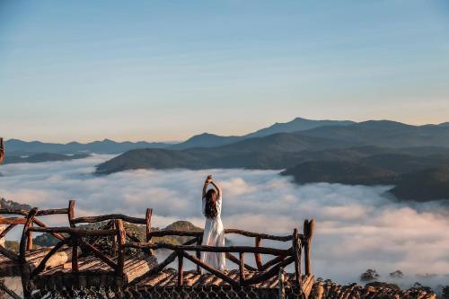 a bird standing on top of a mountain with clouds at holtel Tâm An in Da Lat
