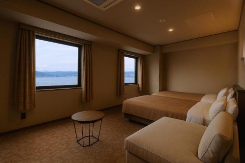 a hotel room with two beds and a couch at Rako Hananoi Hotel in Suwa