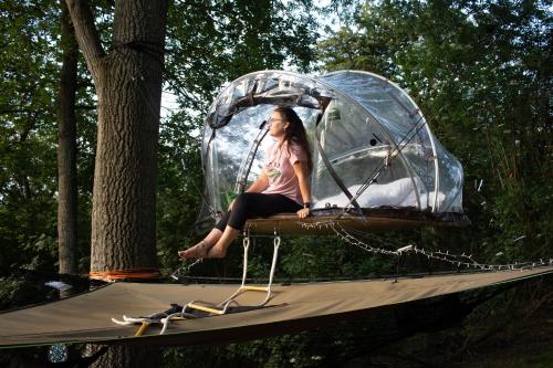a woman sitting on a table in a bubble tent at Tiny bubble Tree Tent in private woodland in Kent