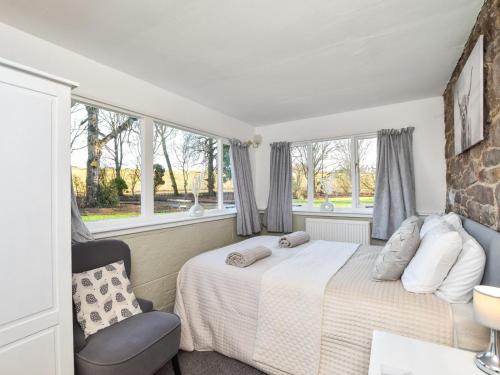 a bedroom with a bed and a chair and windows at 7 Bed in Cupar oc-81242 in Cupar