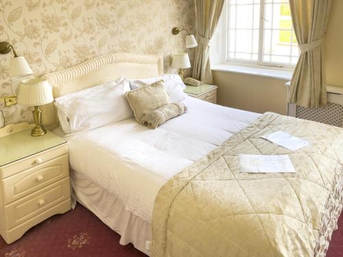 a bedroom with a large white bed and a window at Haddon House Hotel in Bridport