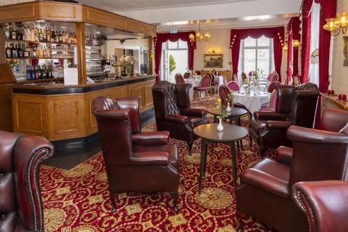 a restaurant with leather chairs and a bar at Haddon House Hotel in Bridport