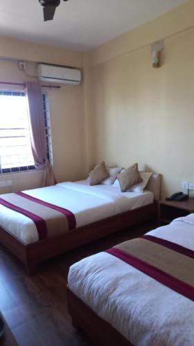 una camera da letto con due letti in una stanza di Hotel Global Unique a Pokhara