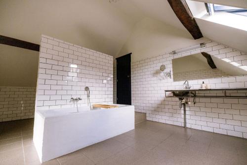 ein weißes Badezimmer mit Badewanne und Waschbecken in der Unterkunft Le Petit Hômage in Lanaken