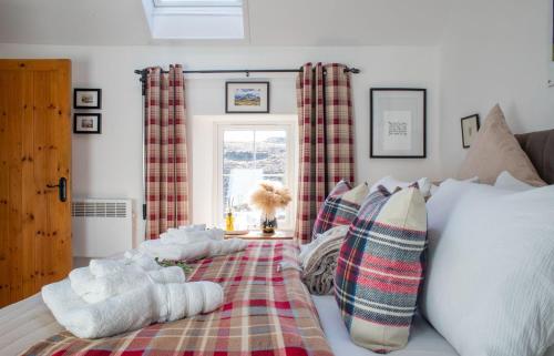 a bedroom with a bed with plaid pillows and a window at The Cottage, 7 Struanmore in Struan