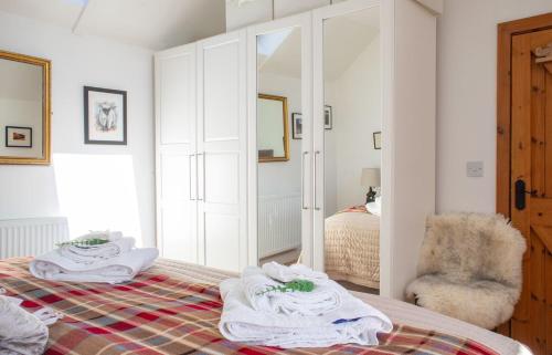 a bedroom with a bed and a chair and a mirror at The Cottage, 7 Struanmore in Struan