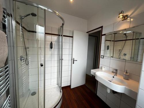 a bathroom with a glass shower and a sink at Hôtel La Gibecière in Lohéac