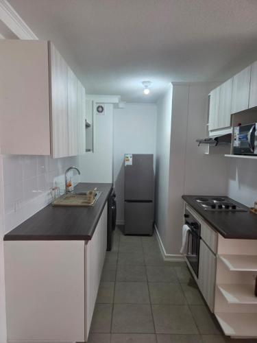 a kitchen with white cabinets and a refrigerator at Pacific blue cómodo y familiar in La Serena