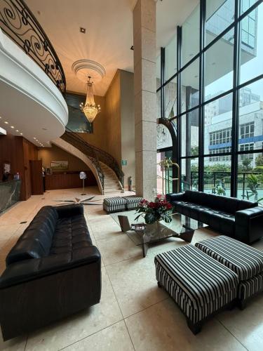 a lobby with black leather furniture and a staircase at Master Plaza Hotel in Barbacena