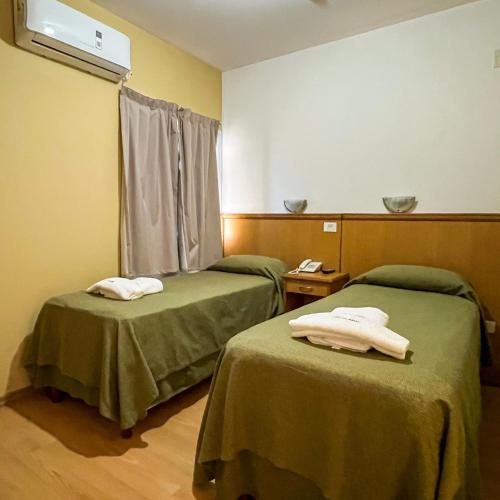 two beds in a hospital room with green sheets at Urunday Apart Hotel in Posadas