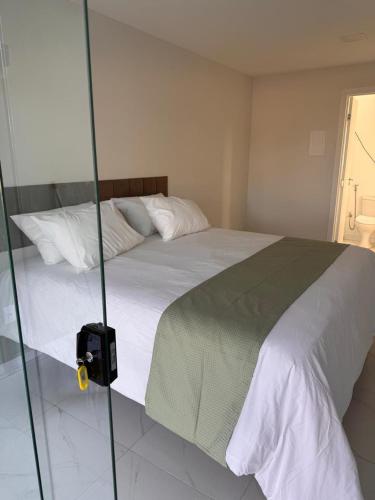 a bed in a bedroom with a glass wall at pousada Maria da Fé in Vera Cruz de Itaparica