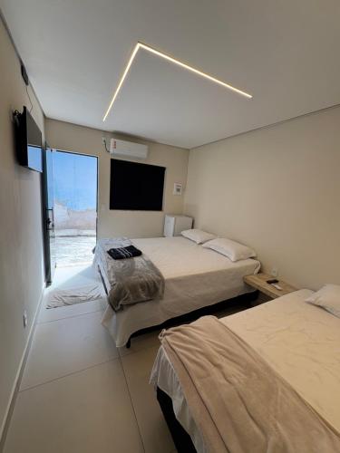 a bedroom with two beds and a large window at Suítes Pousada Canaã in Araxá