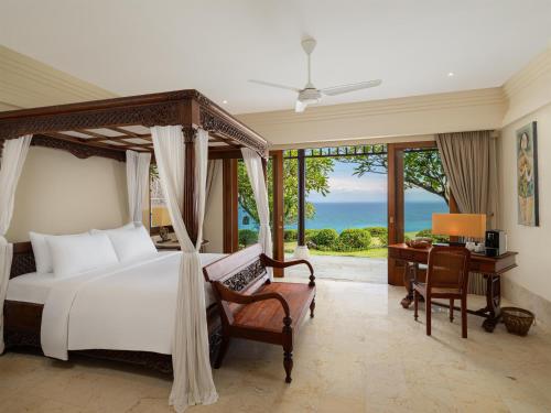 a bedroom with a bed and a desk and windows at Radisson Blu Resort & Villas Bali Uluwatu in Uluwatu