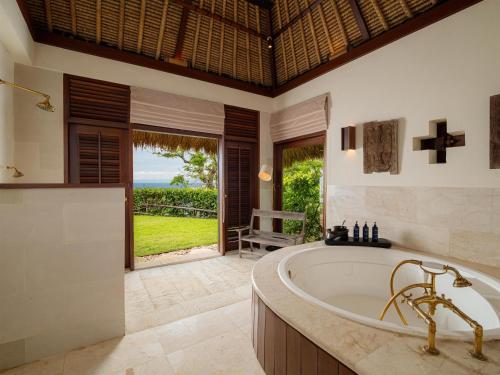 a bathroom with a tub and a view of the ocean at Radisson Blu Resort & Villas Bali Uluwatu in Uluwatu
