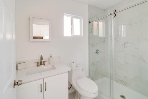 a white bathroom with a toilet and a shower at 13 Mi to Universal Studios: Renovated Cottage! in Los Angeles