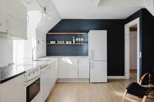 a kitchen with white appliances and a black wall at Odense Doublex Penthouse in Odense