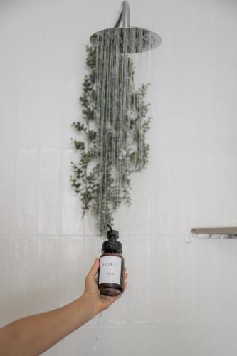 a person holding a clock in front of a shower at Sout Huijs Langebaan with hot tub in Langebaan