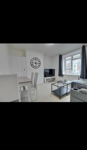 a living room with a table and a clock on the wall at Flat in Portsmouth in Portsmouth