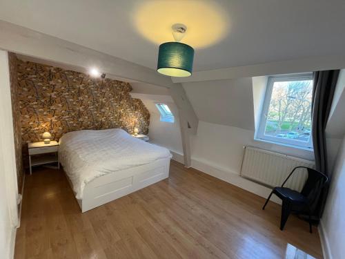una camera da letto con un letto e una sedia di Sainte Cécile a Boulogne-sur-Mer