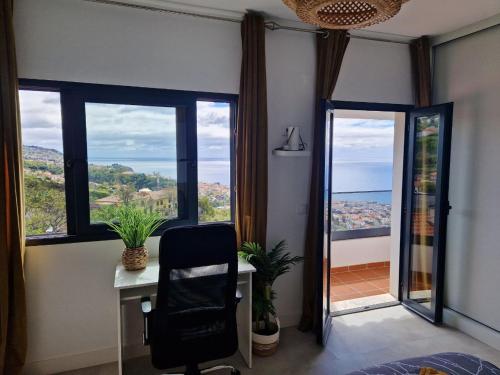 a office with a desk and a chair and windows at CoLiving Funchal in Funchal